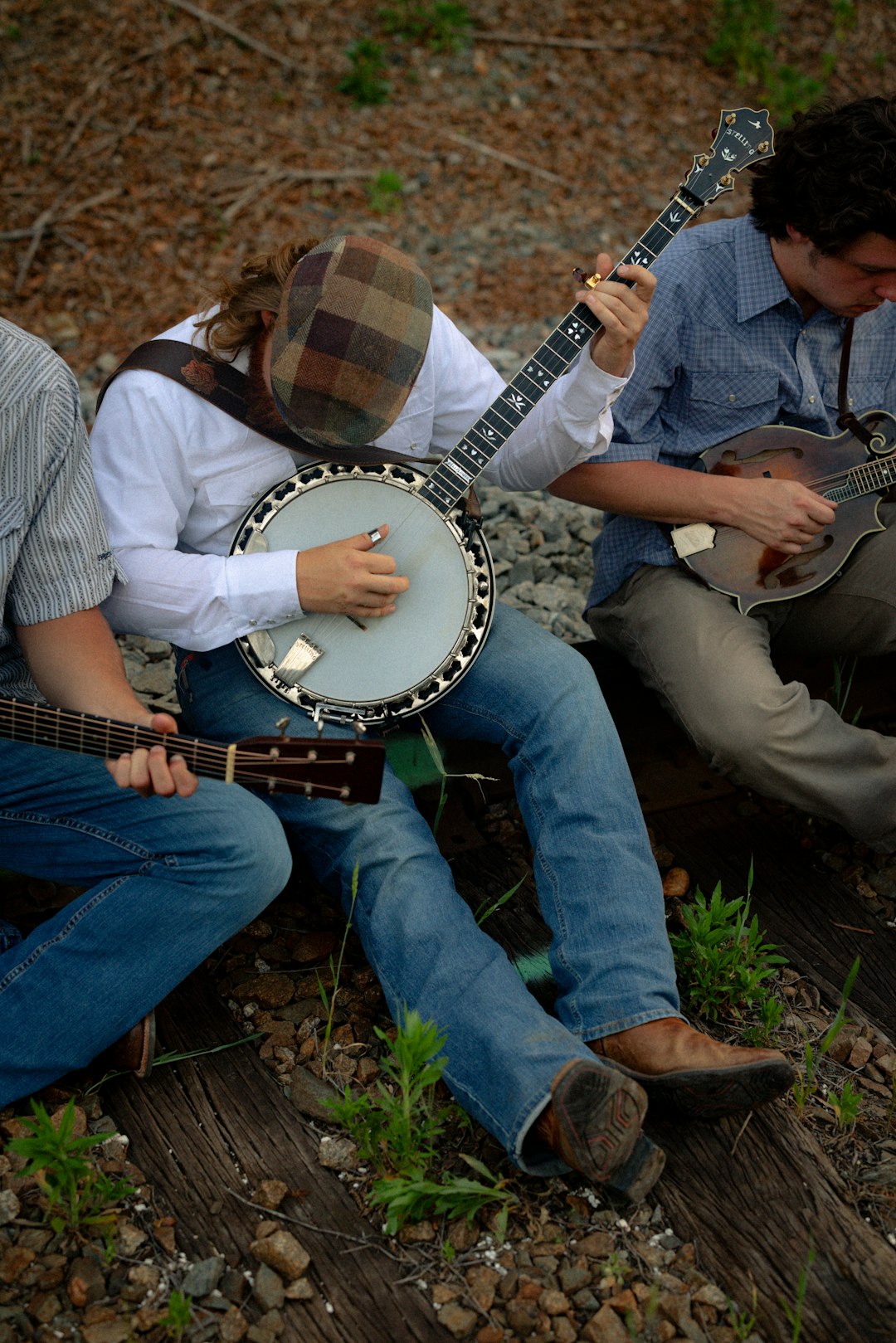 Bluegrass musicians playing banjo, guitar and mandolin in an outdoor performance; illustrative, not a portrait of Ralph Stanley